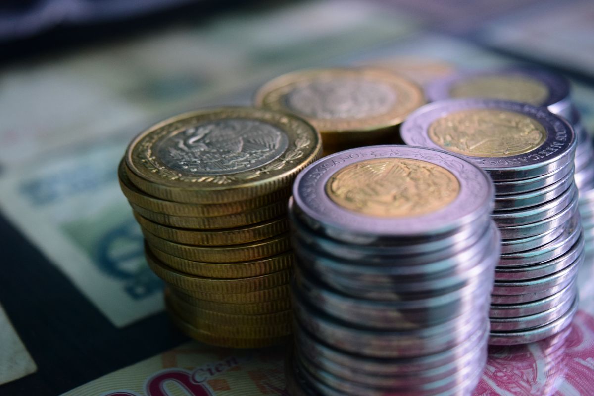 Stacked gold and silver coins on banknotes symbolizing accumulated wealth