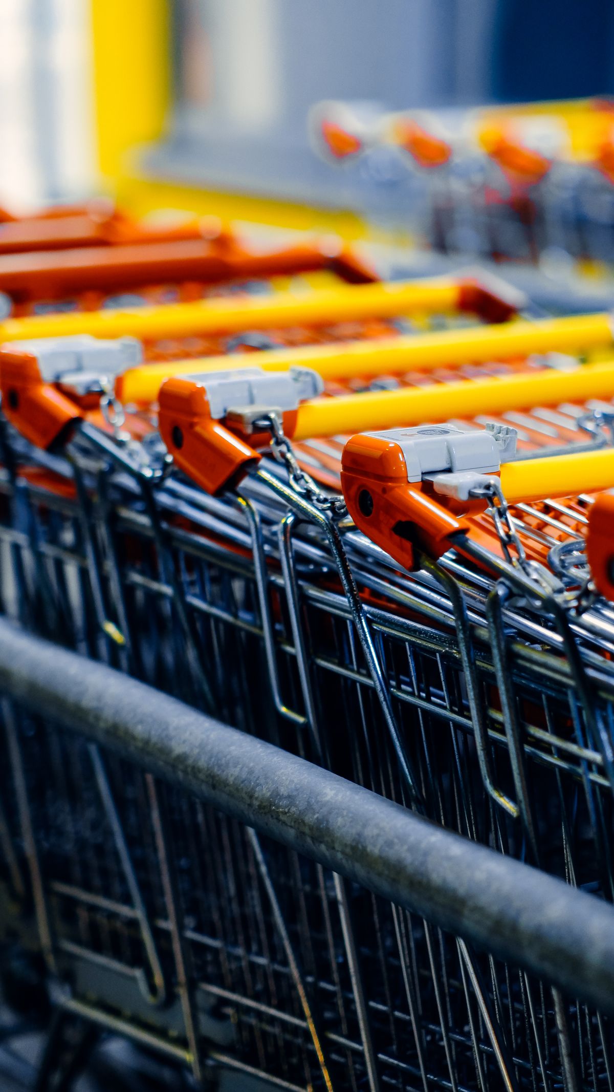 Row of orange-handled shopping carts lined up in a retail store