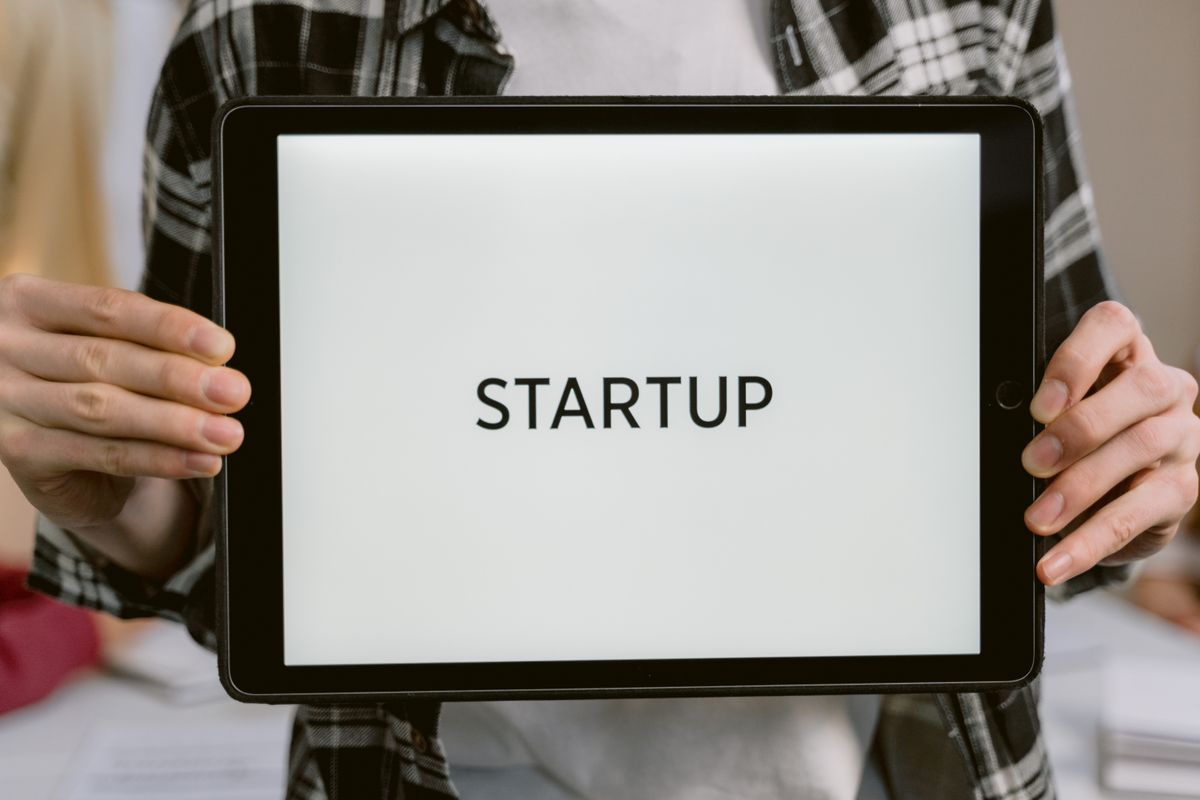A hand holding a tablet displaying the word startup