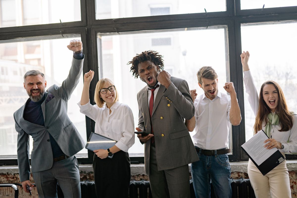 A diverse group of young professionals celebrating success with raised fists