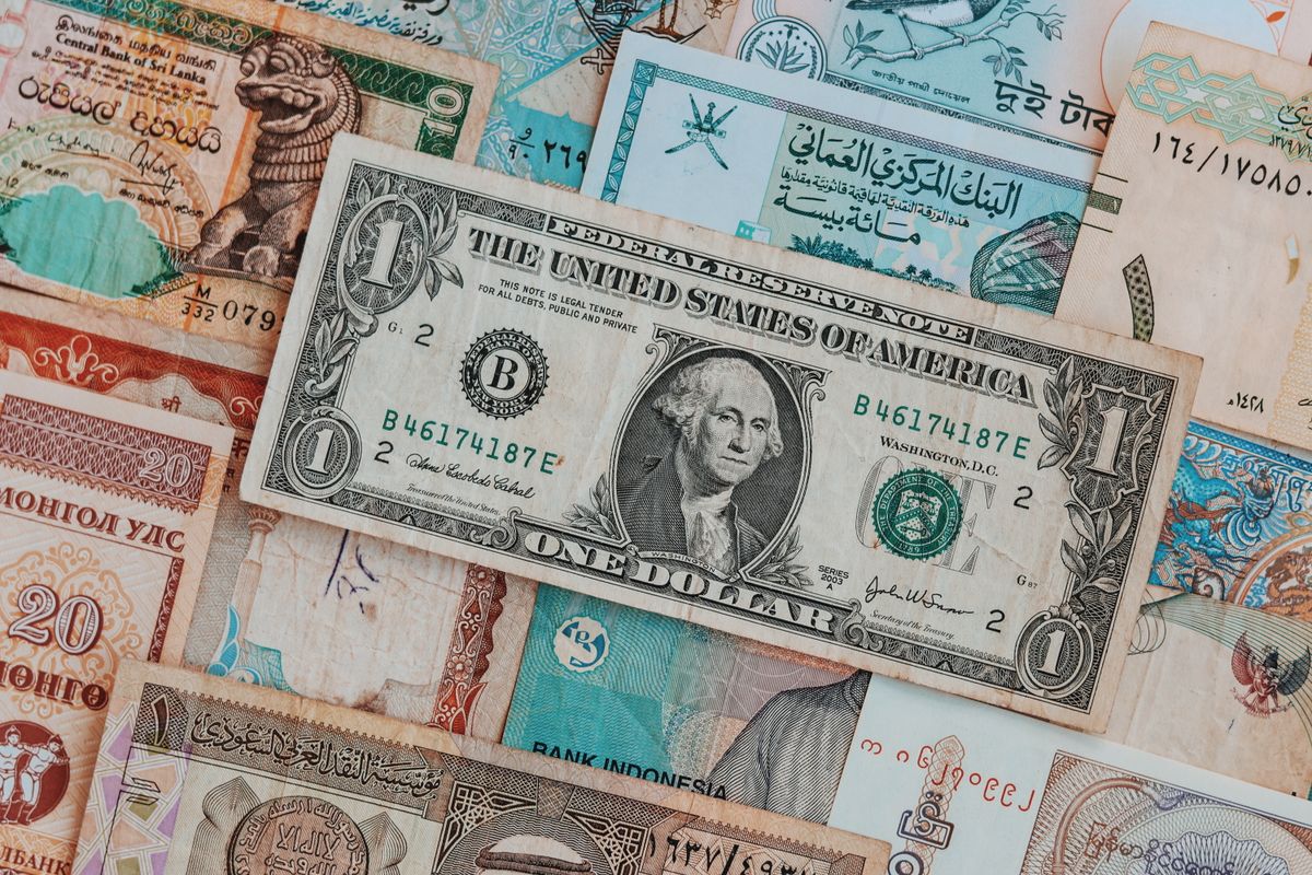 A stacked collection of international banknotes topped with a US dollar bill