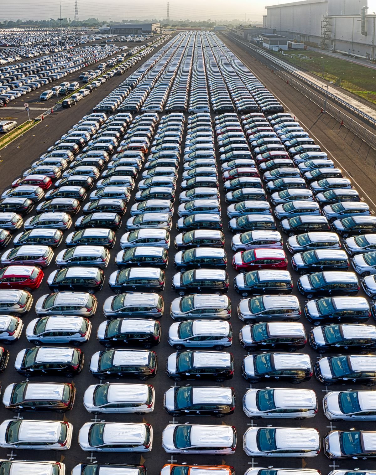 Aerial view of hundreds of newly manufactured cars parked outside an auto plant