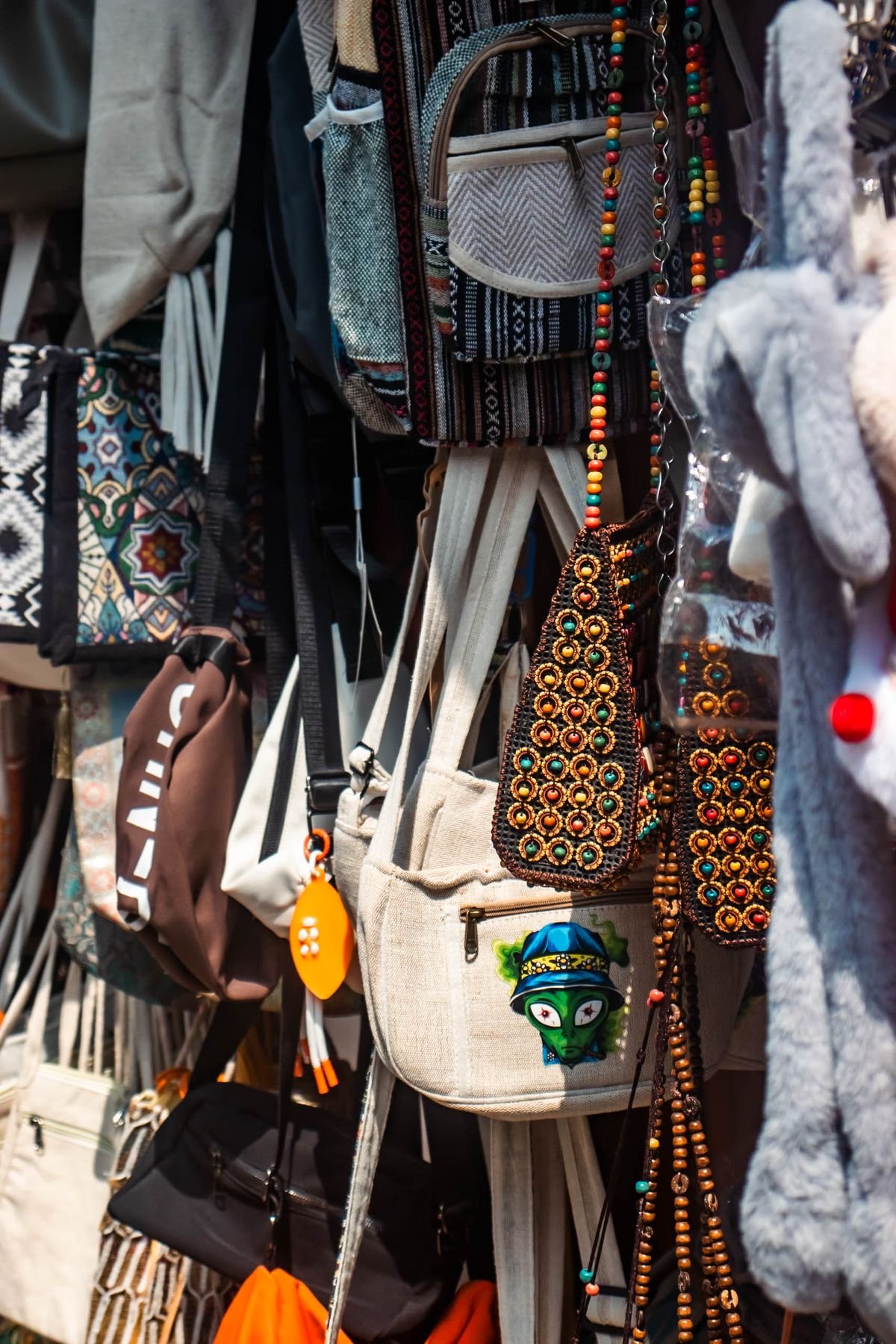 Colorful merchandise and handmade bags on display at a busy retail street stall
