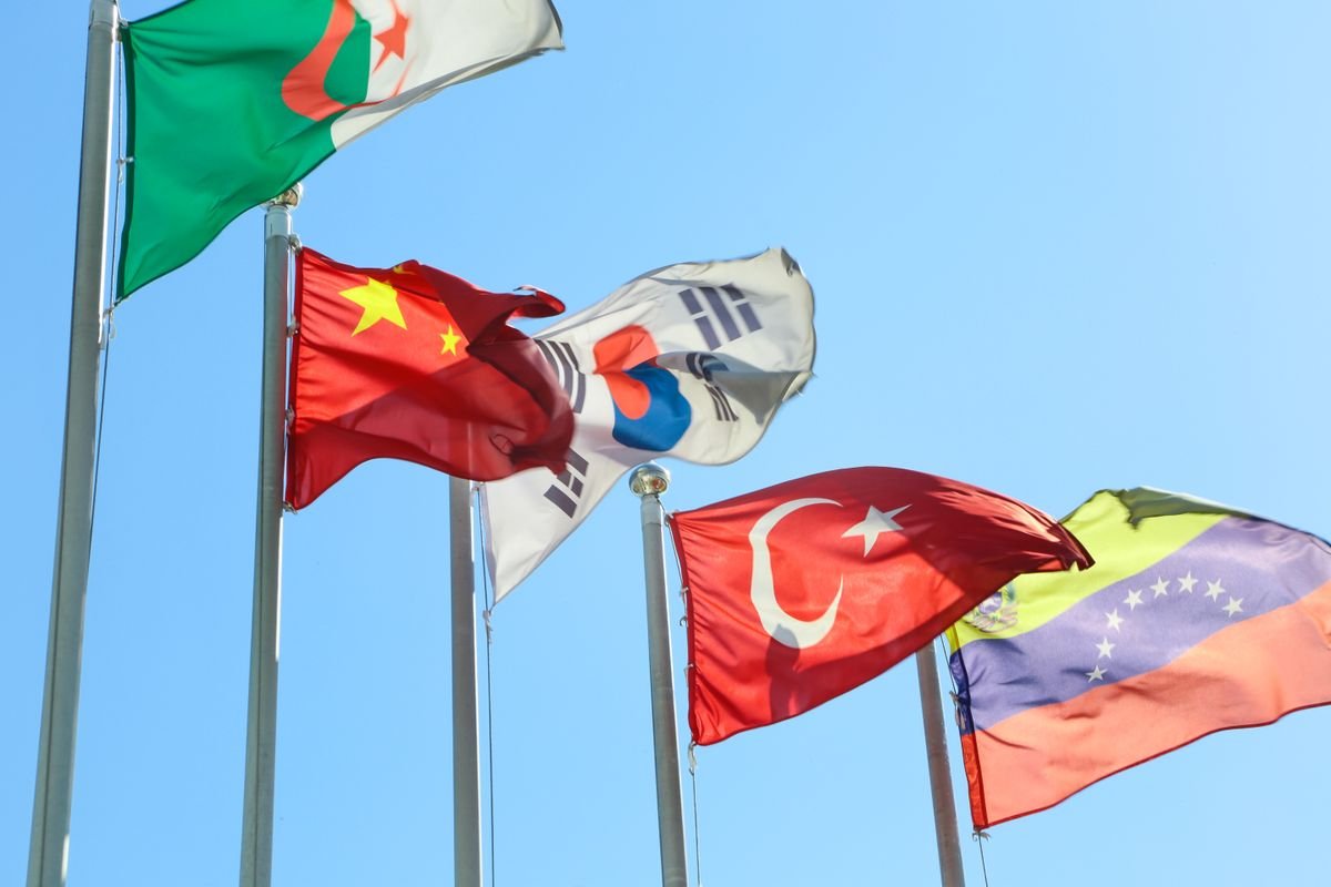 Several national flags waving on flagpoles under a clear blue sky, symbolising the BRICS nations